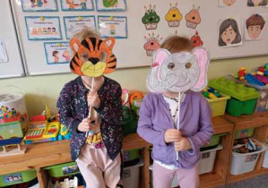 Dwie dziewczynki pozują do zdjęcia z wykonanymi przez siebie maskami zwierząt