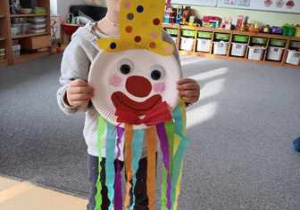 Dziewczynka pozuje do zdjęcia z pracą plastyczną pt. "Karnawałowy klaun"