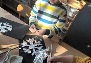 Chłopiec urywa kawałki folii aluminiowej podczas działań plastycznych