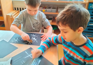 dzieci malują na czarnych kartonach techniką "Twal" używając białej farby
