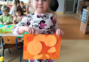 dziewczynka prezentuje abstrakcyjną pracę w odcieniach koloru pomarańczowego