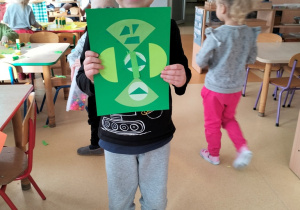 chłopiec prezentuje abstrakcyjną pracę w odcieniach koloru zielonego