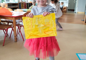 dziewczynka prezentuje abstrakcyjną pracę w odcieniach koloru żółtego