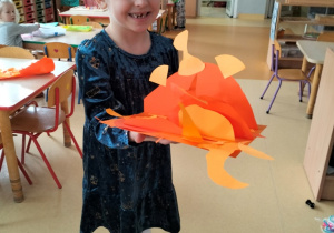 dziewczynka prezentuje abstrakcyjną pracę w odcieniach koloru pomarańczowego
