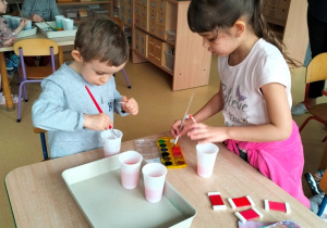 dzieci farbują wodę farbami na różne odcienie czerwonego