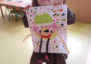 Dziewczynka trzyma w dłoniach swoją pracę plastyczną przedstawiającą pączka