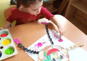 Dziewczynka stempluje placem umoczonym w farbie kolorowe kropki