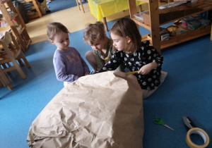 Dzieci oklejają pączka szarym papierem