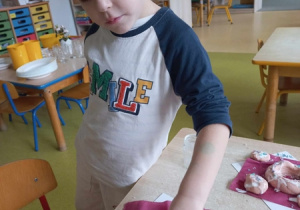 Chłopiec dekoruje pączka kolorowymi groszkami