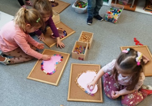 Dzieci układają przedmioty na kartce w kształcie serca