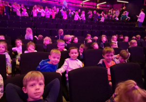 Dzieci siedzą i czekają w teatrze na przedstawienie