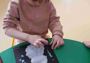 Dziewczynka maluje śnieg palcem odbitym w farbie