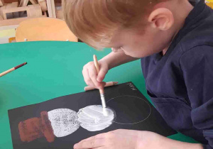 Chłopiec maluje farbami bałwana