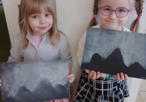 Dziewczynki trzymają w rękach swoje prace przedstawiające zorze polarne