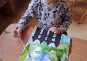 Franio maluje zieloną akwarelą tło swojej pracy