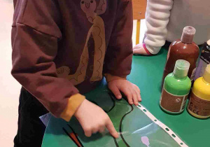 Chłopiec rozprowadza farbę na planszy z dinozaurem