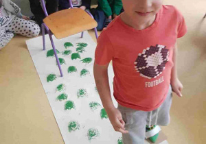 Chłopiec odwzorowuje ślady dinozaurów za pomocą stempli na stopach
