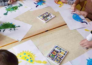 Dzieci rysują dinozaury z wykorzystaniem papierowych talerzyków