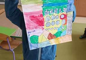 Chłopiec trzyma w dłoniach namalowaną przez siebie na dużym arkuszu kolorowaną skarpetkę
