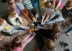 Dzieci siedzą na dywanie i stykają się kolorowymi skarpetkami