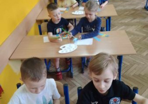 Dzieci w trakcie przyklejania gotowych elementów z papieru