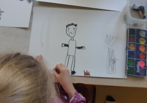 Dziewczynka rysuje chłopca, któremu jest smutno z powodu zanieczyszczonej planety Ziemi