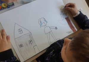 Chłopiec rysuje smutne dzieci z powodu zanieczyszczonego powietrza