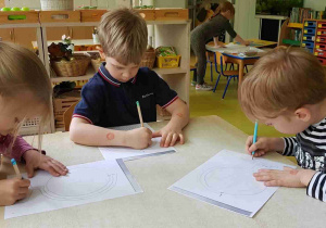 Dzieci podczas ćwiczenia graficznego z kartą pracy przedstawiającą globus