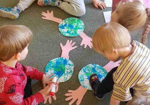 Dzieci przyklejają wycięte dłonie z papieru