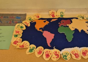 Wystawa prezentująca wykonane przez dzieci prace: mapy świata, odciśnięte dłonie dzieci, napis Nasza Ziemia w naszych rękach, plakat jak dbamy o Ziemię