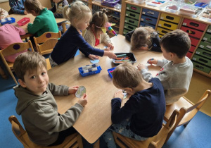 Dzieci siedzą przy stoliku i kolorują mapę świata