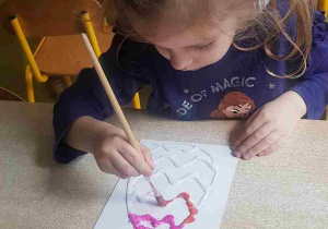 Dziewczynka koloruje solną pisankę akwarelami