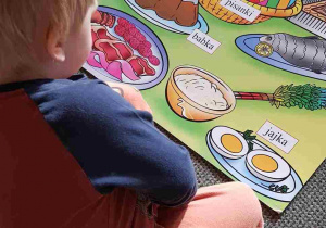 Chłopiec ogląda planszę z wielkanocnymi potrawami