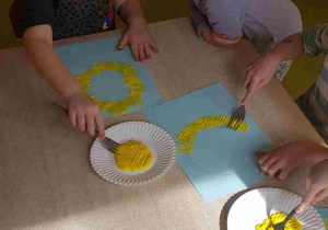 Dzieci stemplują kurczaczki żółtą farbą