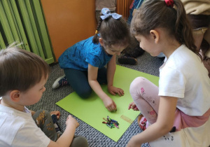 Dzieci rysują kredkami rysunki na dużych kolorowych kartkach