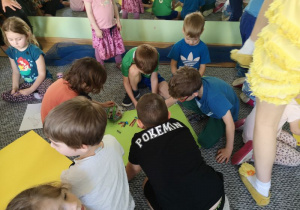 Dzieci rysują kredkami rysunki na dużych kolorowych kartkach