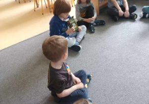 Dzieci siedzą w kręgu na dywanie i poznają zapach kakao