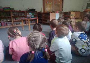 Dzieci siedzą na dywanie i oglądają filmik edukacyjny