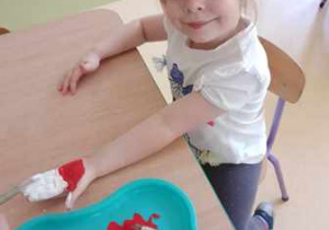 Dziewczynka pozuje do zdjęcia z dłonią umalowaną w biało-czerwonych barwach