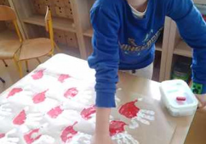 Chłopiec odbija na plakacie dłoń pomalowaną barwami narodowymi