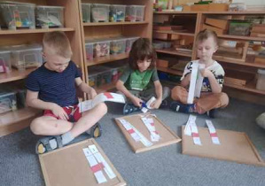 Chłopcy podczas wycinania pasków papieru z elementami flagi Polski