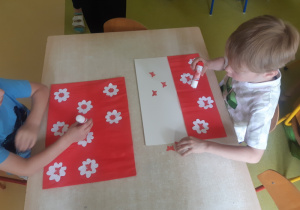 Dzieci naklejają biało - czerwone kwiaty