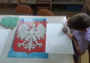 Chłopiec rysuje kontury Polski