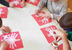 Dzieci przy stole malują szczegółowe elementy godła
