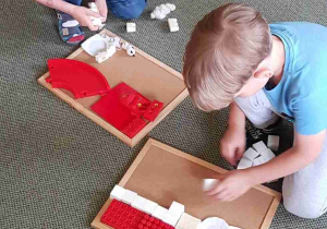 Chłopcy układają biało-czerwoną flagę z klocków i plastikowych elementów