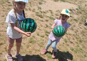 Dziewczynki trzymają w dłoniach piłki przypominające arbuzy