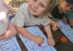 Chłopiec koloruje ilustrację jabłka podczas warsztatów edukacyjnych