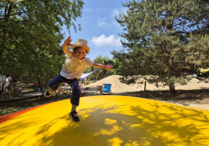 Dziewczynka skacze na kolorowej poduszce