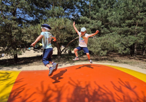 Dwóch chłopców skacze na kolorowej poduszce