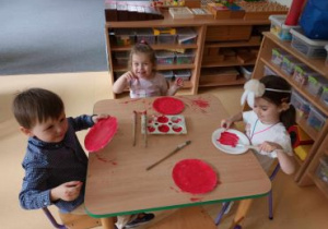 Dzieci malują papierowe talerzyki na czerwono